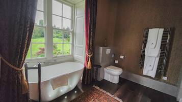 A bathroom with a bathtub, toilet, and a window with curtains.