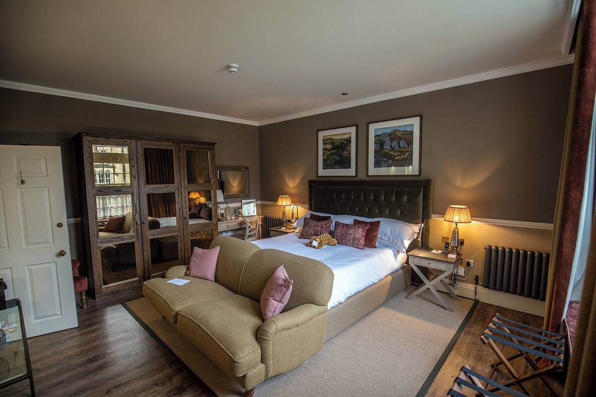 A bedroom with a bed, a sofa, a wardrobe, and a radiator.