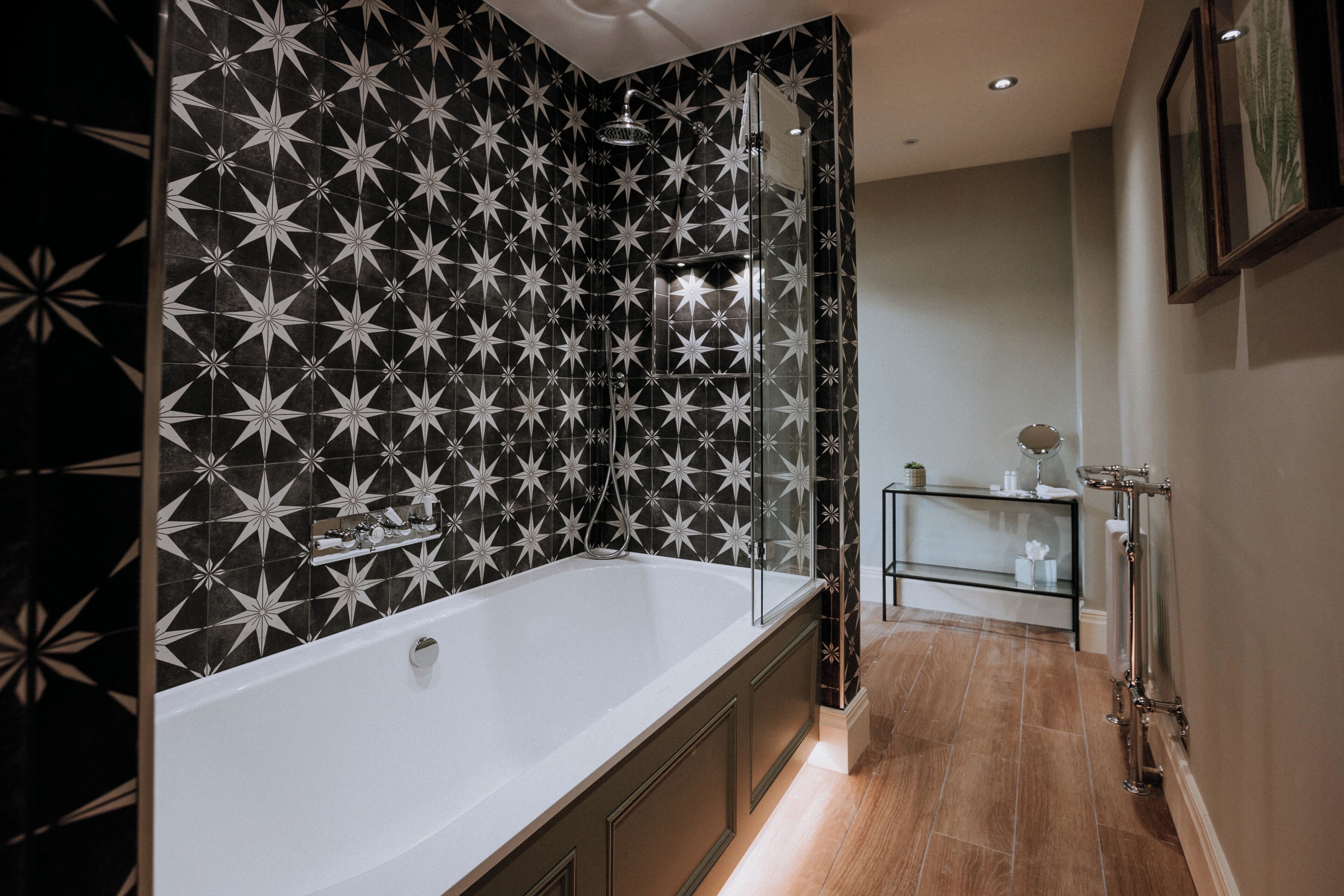A modern bathroom with a large bathtub, a glass shower enclosure, and a tiled backsplash with a star pattern.