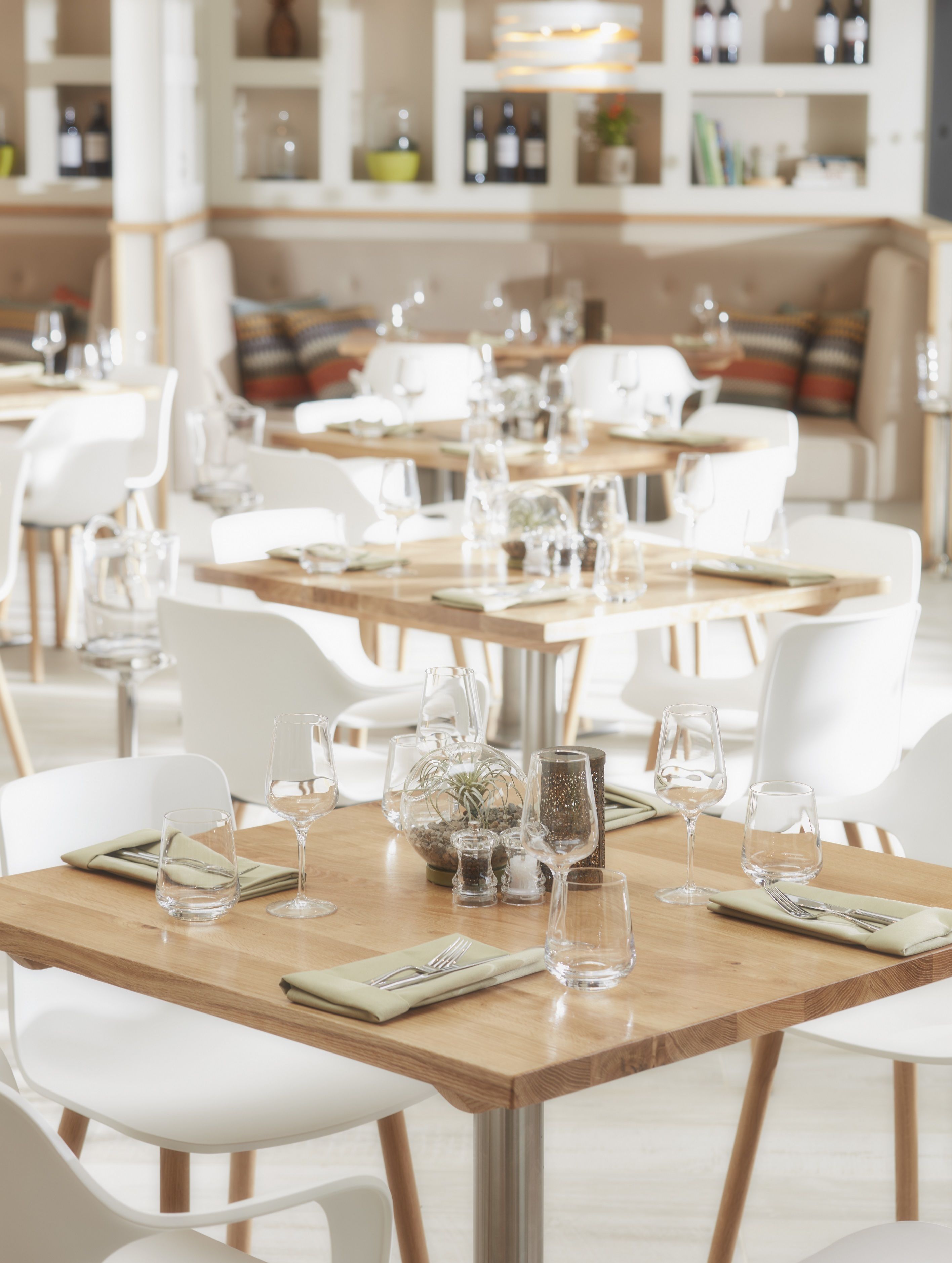A restaurant with multiple tables set for dining, each with white chairs and clear glassware.