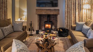 Una sala de estar acogedora con chimenea, dos sofás, una mesa de centro y un televisor montado en la pared.