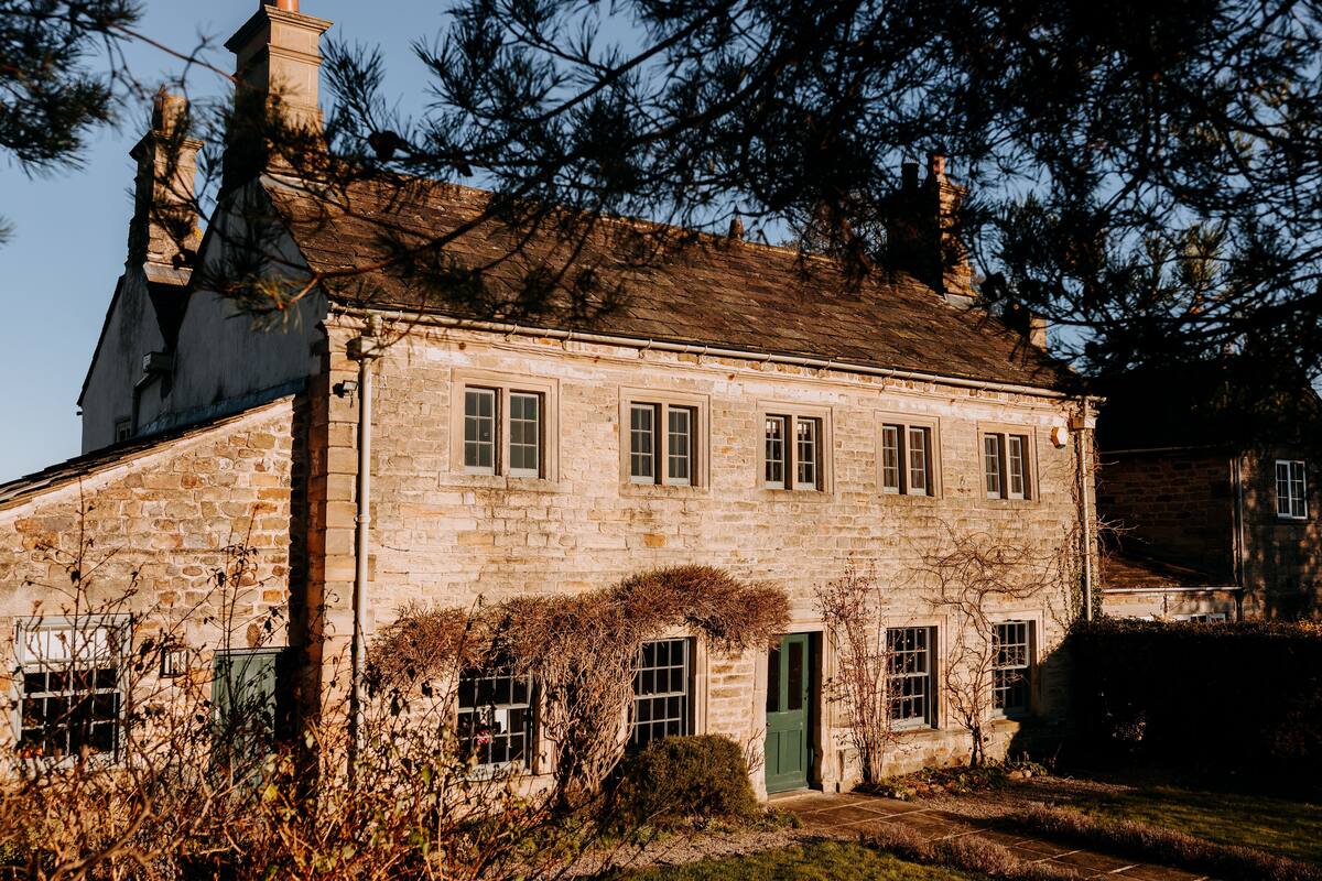 A stone building with a green door, multiple windows, and a chimney.