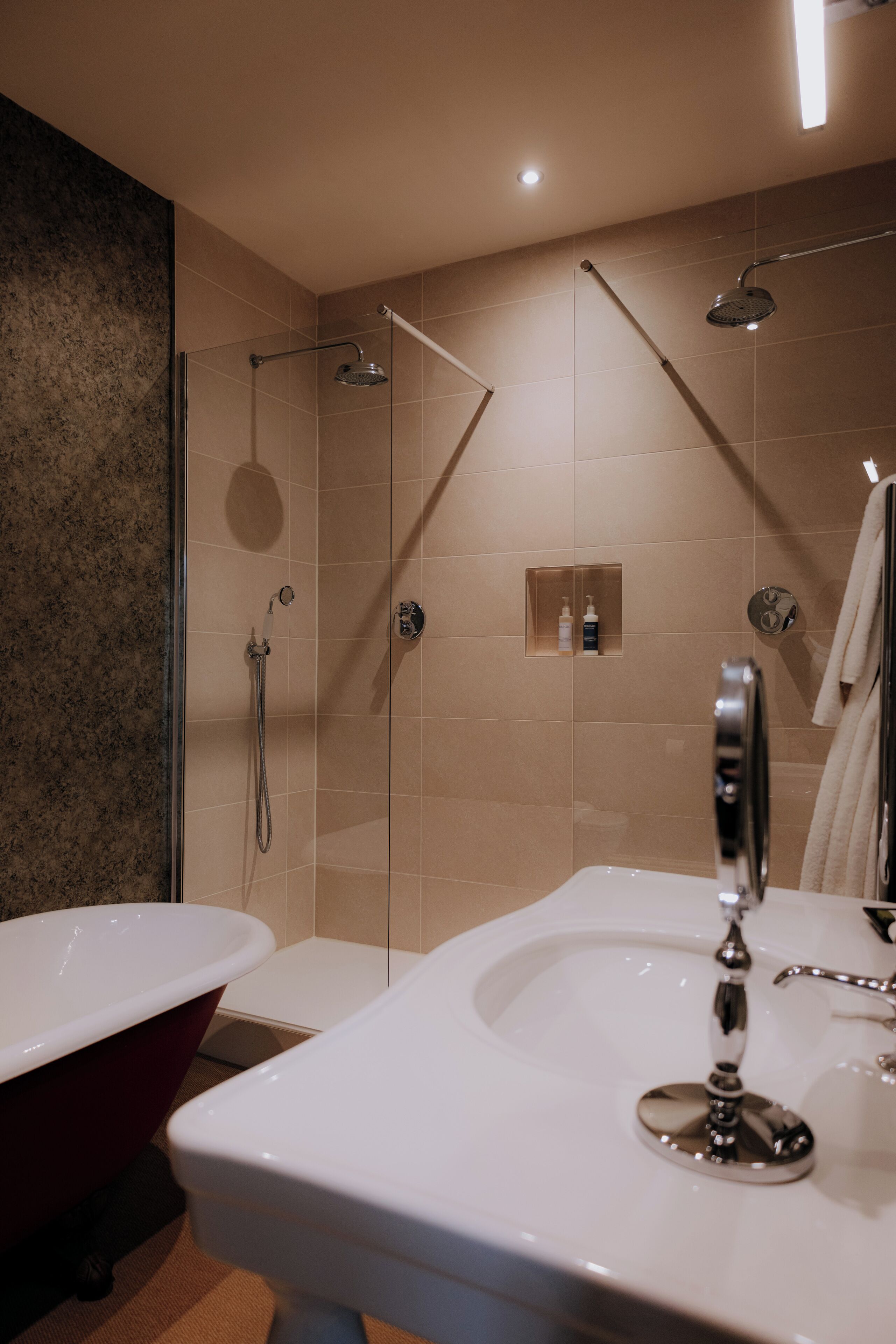 A modern bathroom with a glass-enclosed shower, a freestanding bathtub, and a vanity with a mirror.