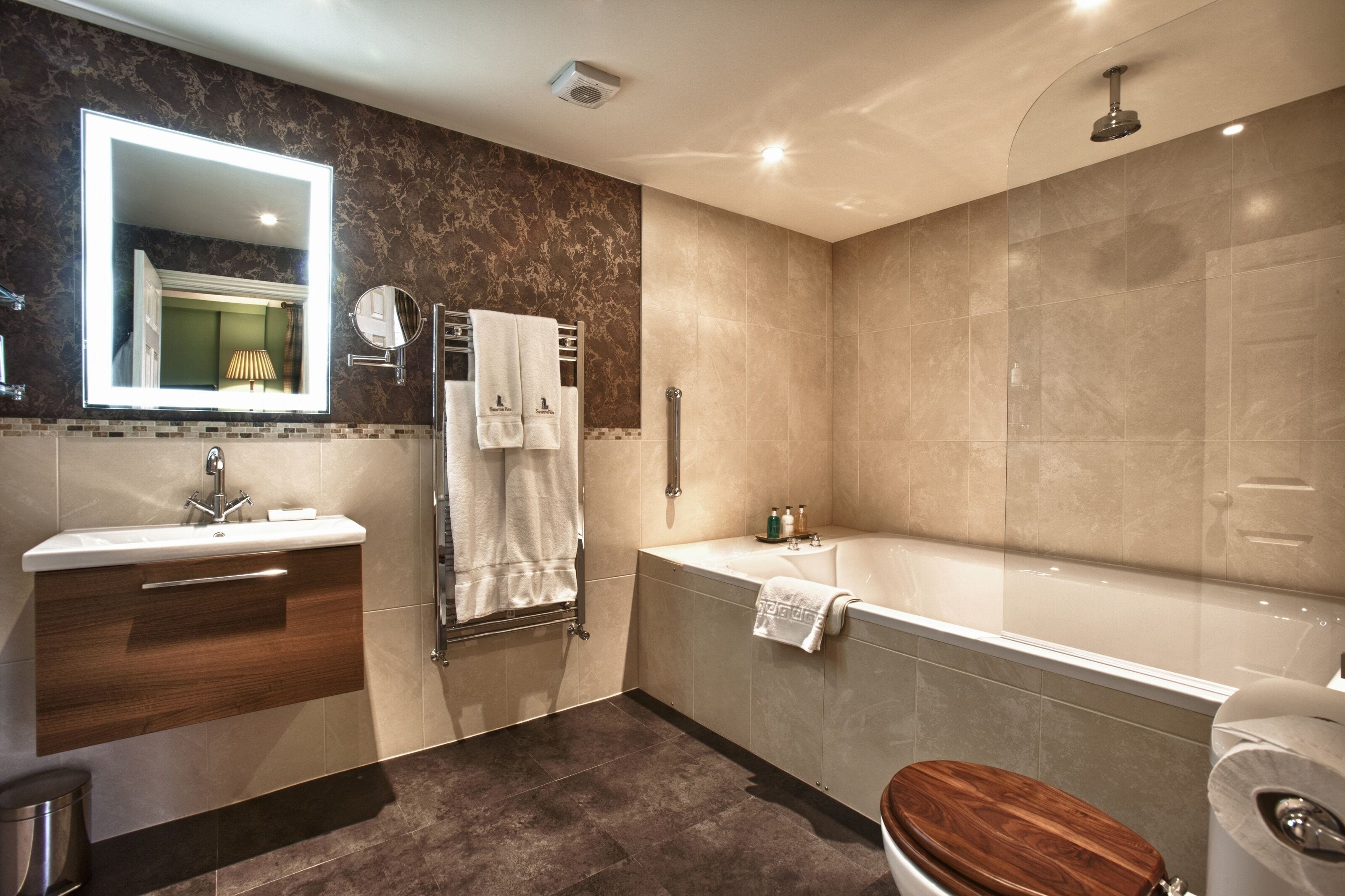 Ein modernes Badezimmer mit Waschtisch, Spüle, Spiegel, Handtuchhalter, Badewanne und Toilette.