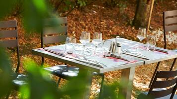 Una mesa de comedor al aire libre con sillas, vasos y cubiertos.