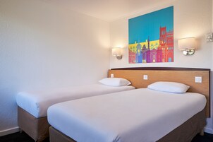 Habitación de hotel con dos camas, un cabecero de madera y un cuadro de un paisaje urbano colorido en la pared.