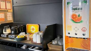 A self-service beverage station with a Tropicana Pure Premium dispenser, coffee makers, and a variety of condiments and snacks.