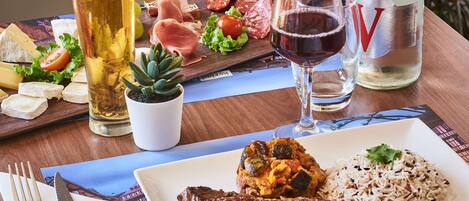 A dining table with a variety of foods including steak, rice, and cheese, along with glasses of beer and water.