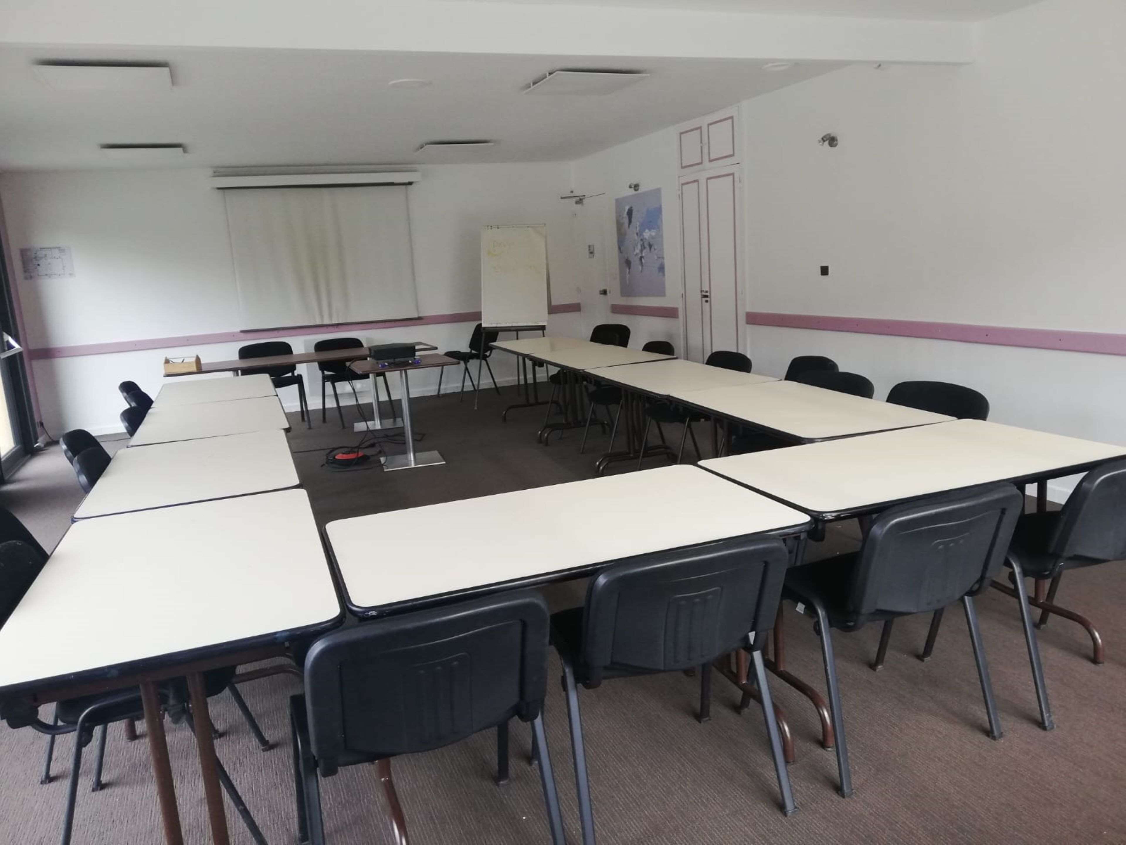 A conference room with long tables and chairs, whiteboard, and posters on the walls.