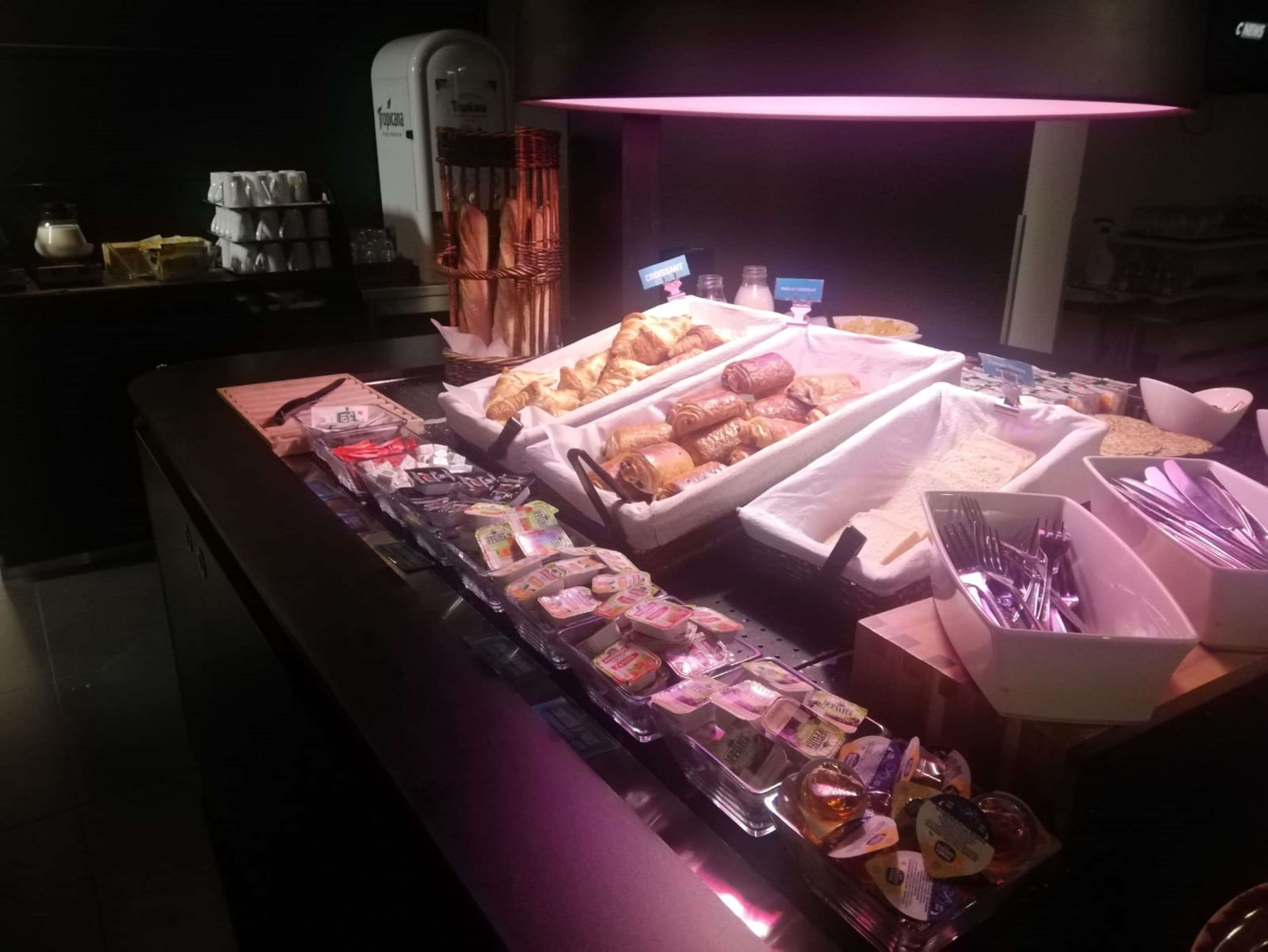 A breakfast buffet with various pastries, sandwiches, and beverages.
