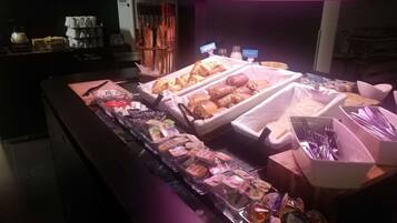 A breakfast buffet with various pastries, sandwiches, and beverages.