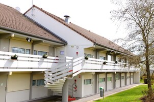 Un hotel de varios pisos con fachada blanca, tejado de tejas y una escalera central.