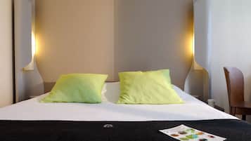 A hotel room with a bed, two pillows, a nightstand, a chair, and a menu on the bed.