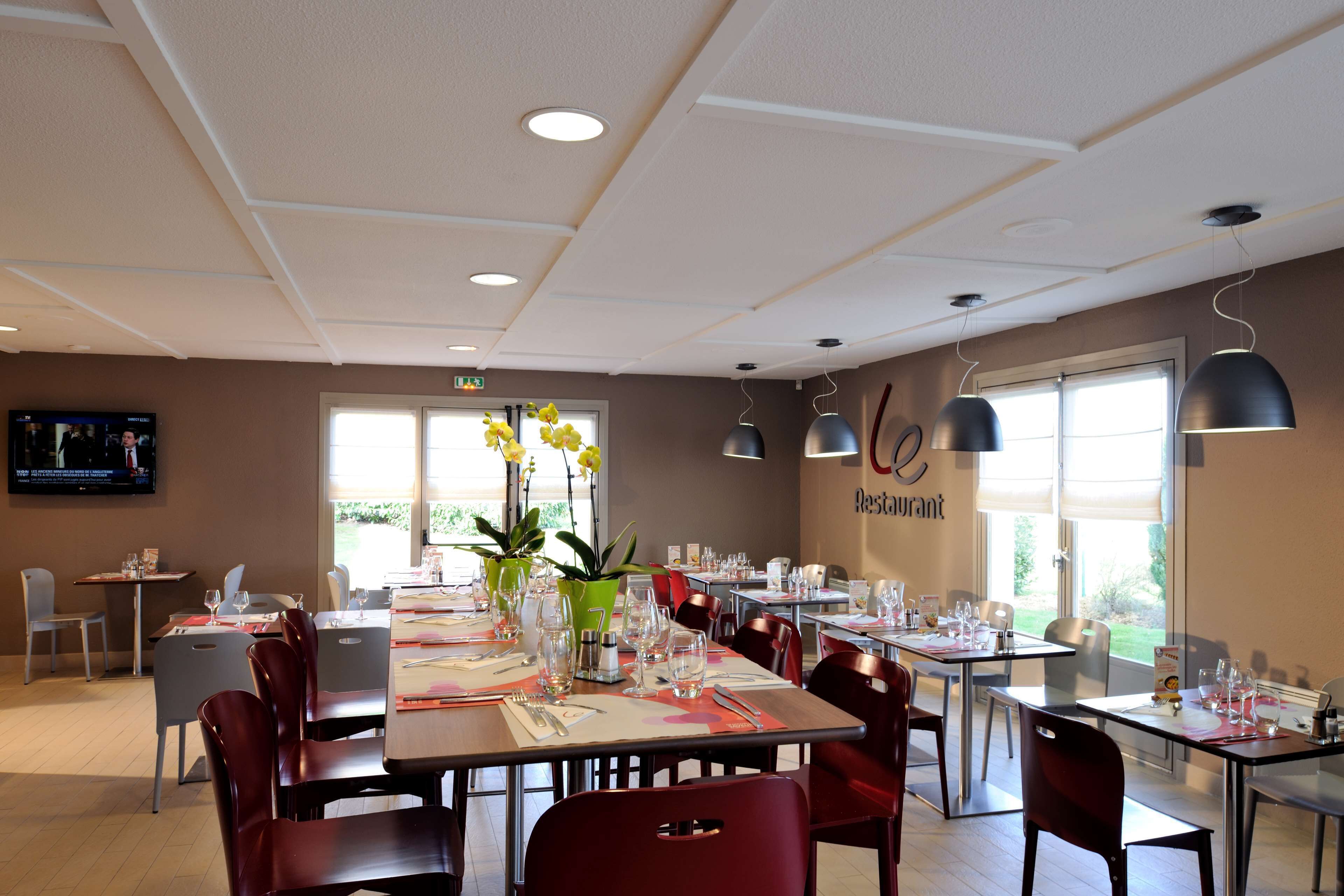 A restaurant with multiple tables, chairs, and potted plants.