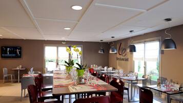 A restaurant with multiple tables, chairs, and potted plants.