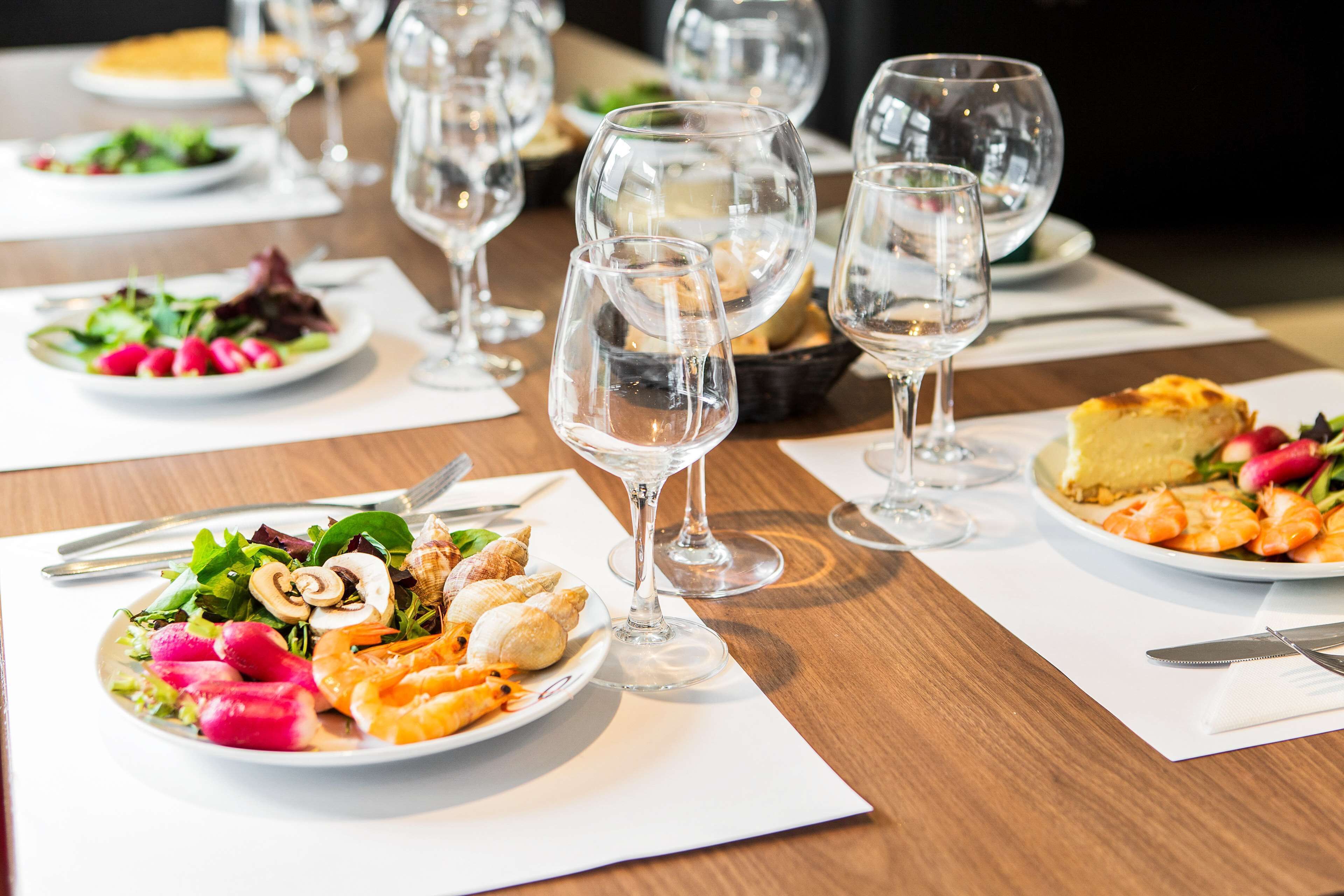 A dining table with plates of food, wine glasses, and cutlery.