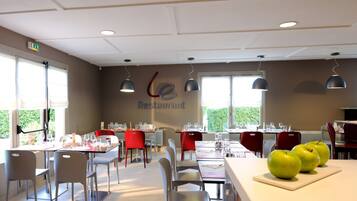 A restaurant with tables set for dining, chairs, and hanging pendant lights.