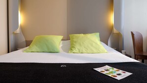 Una cama bien hecha con dos almohadas, una manta negra y un folleto sobre la cama.