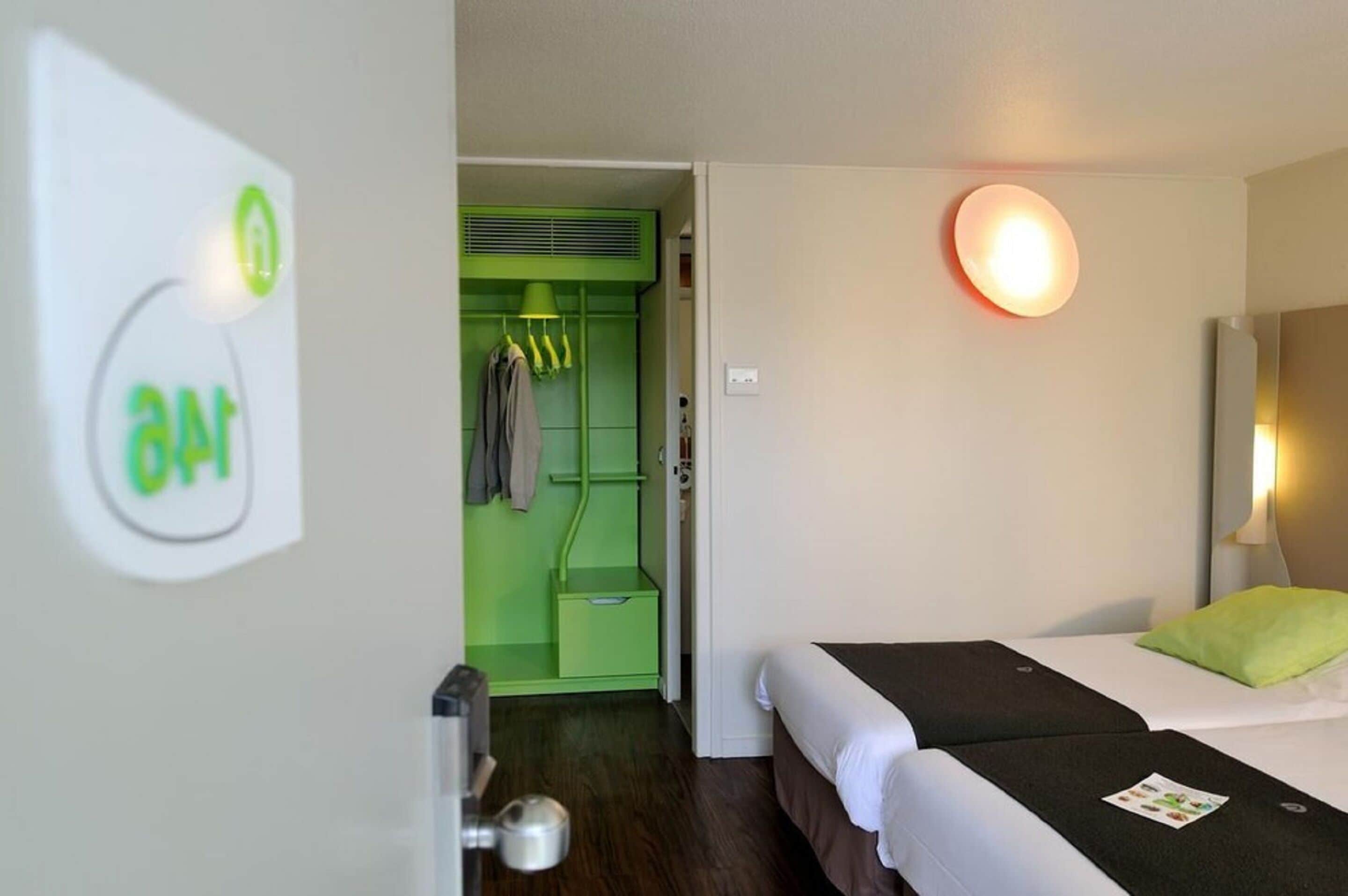 Ein Hotelzimmer mit einem Bett, einem grünen Kleiderschrank und einer Wandleuchte.