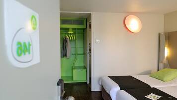 Ein Hotelzimmer mit einem Bett, einem grünen Kleiderschrank und einer Wandleuchte.