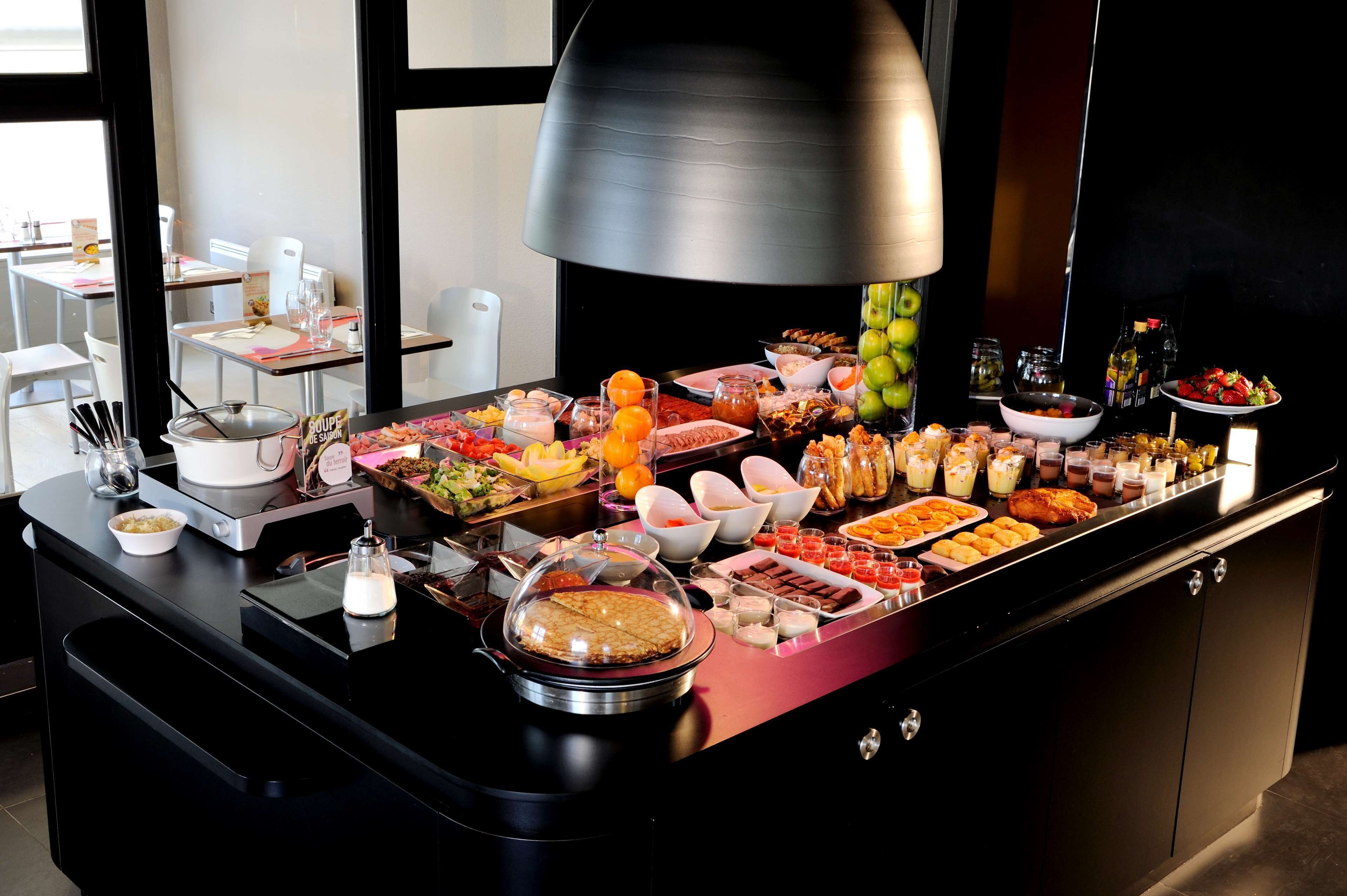 A buffet with a variety of food items and a large black lamp above it.