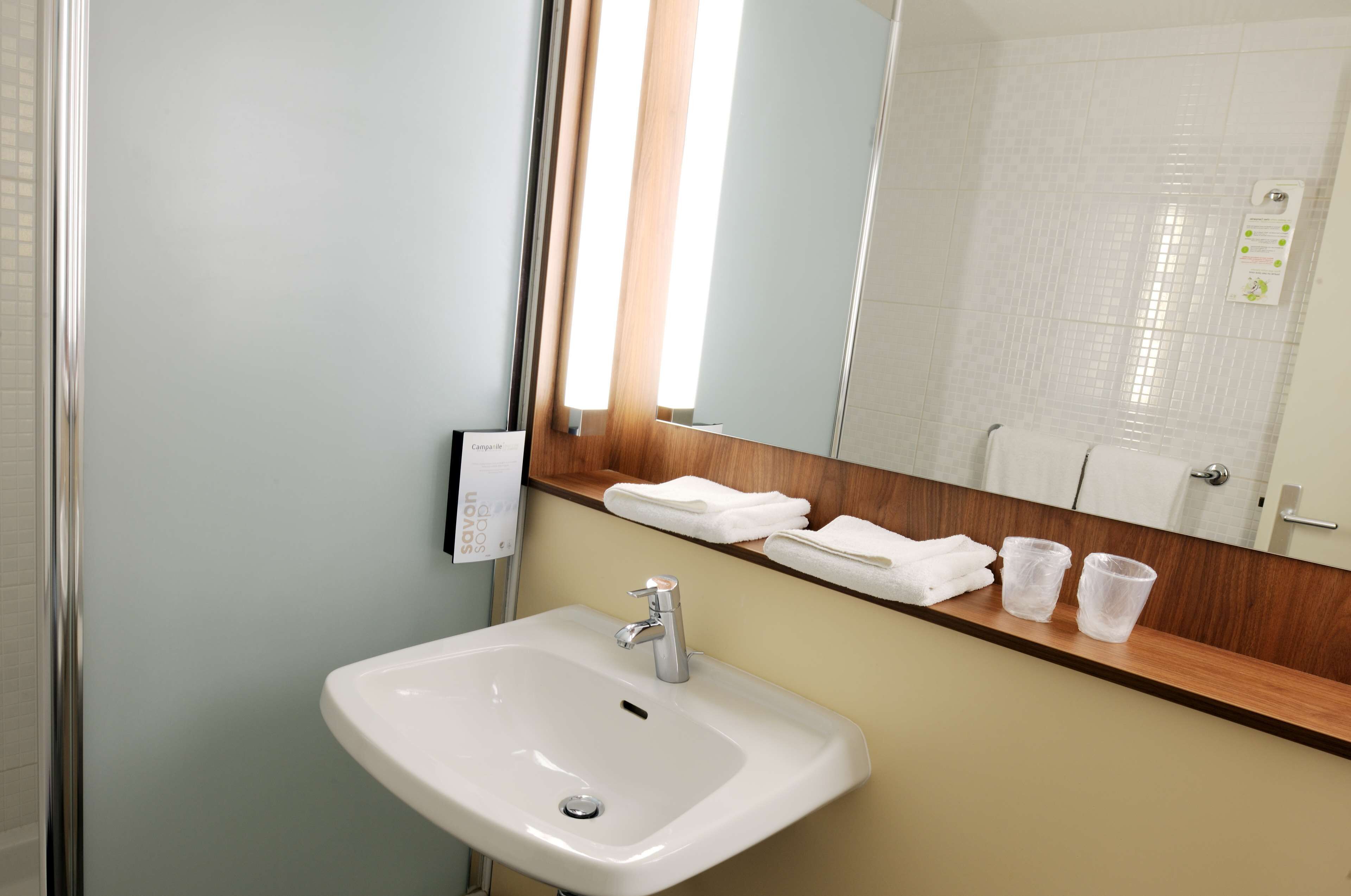 A bathroom with a white sink, a mirror, and a towel rack.