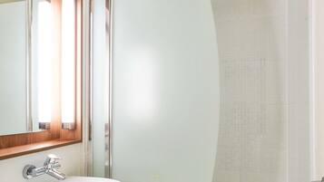 A bathroom with a white sink, a mirror with a wooden frame, and a glass-enclosed shower area.