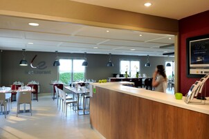 Un interior de restaurante moderno con mostrador de madera, mesas y sillas.