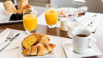 A breakfast setting with croissants, orange juice, and coffee on a table.