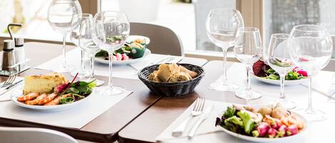 Une table à manger dressée avec des assiettes remplies de nourriture, des verres à vin et des couverts.