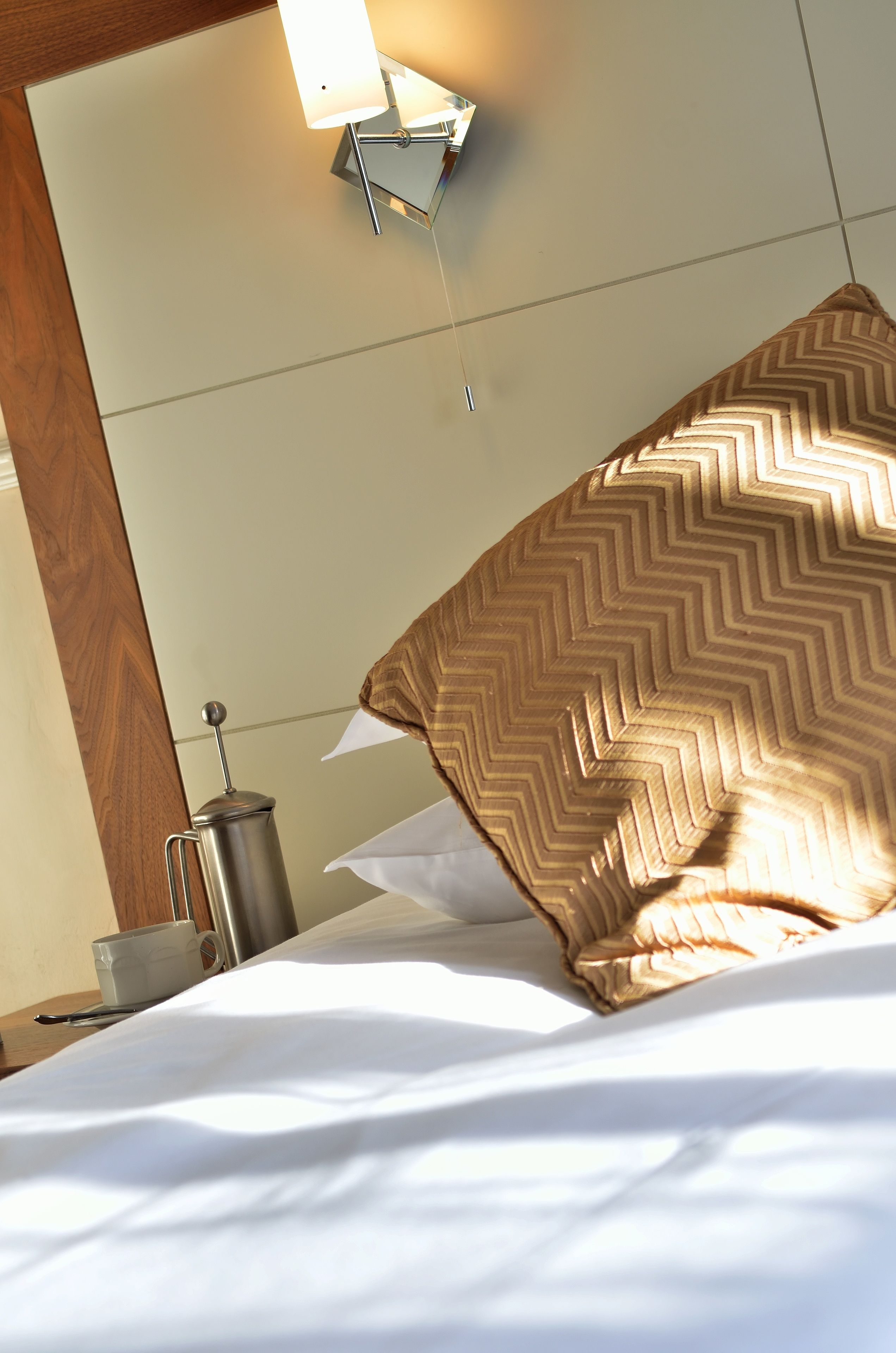 Ein Hotelzimmer mit einem Bett, einem Nachttisch, einer Lampe und einem Spiegel.