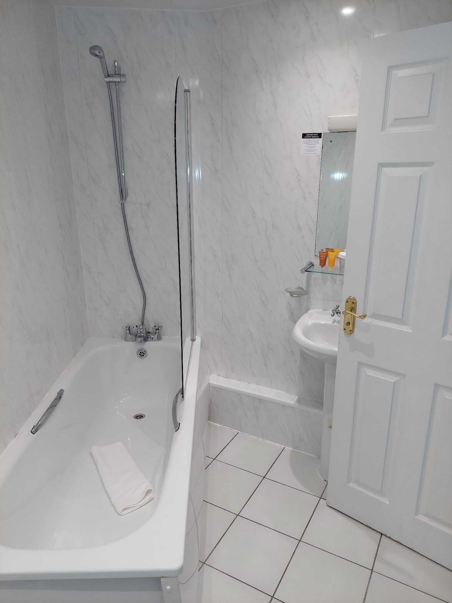 Un bagno con vasca, doccia, lavandino e porta.