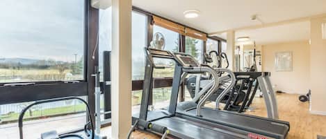 Une salle de sport équipée de tapis de course, d’un vélo d’appartement et d’un appareil d’aviron.