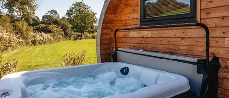 A hot tub with a wooden exterior wall and a window.