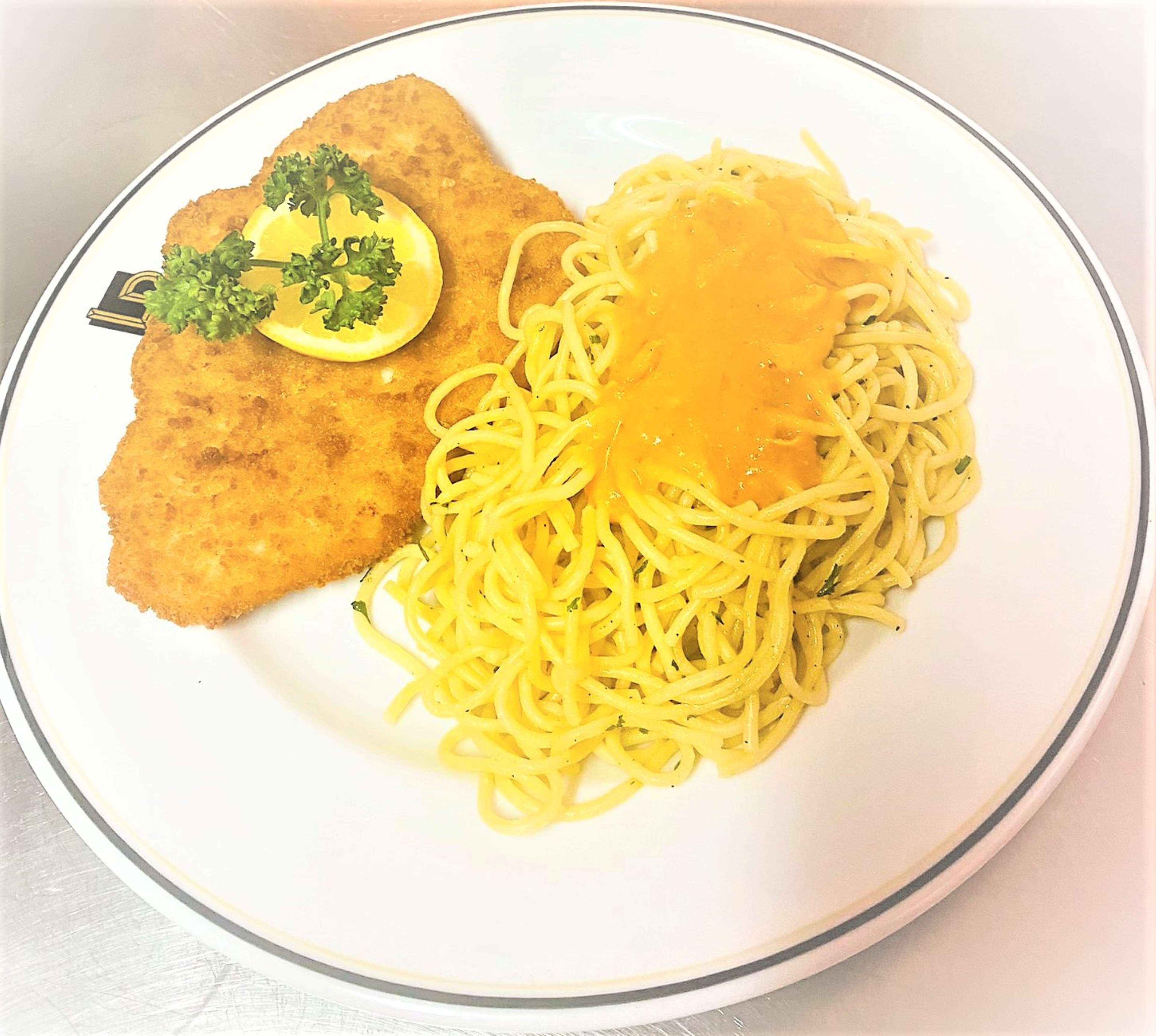 A plate with breaded cutlet, spaghetti, and a lemon wedge.