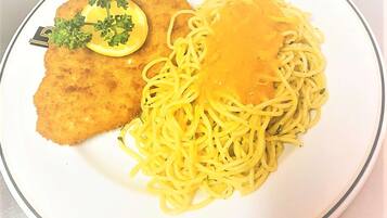 A plate with breaded cutlet, spaghetti, and a lemon wedge.