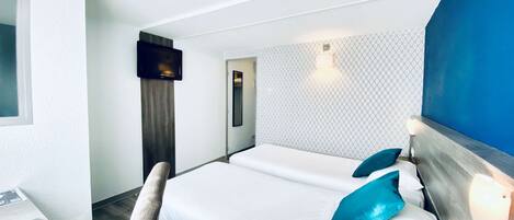 Habitación de hotel con cama, escritorio, televisor y pared con diseño.