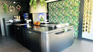 Een moderne keuken met een centraal eiland, inbouwapparatuur en decoratieve elementen zoals planten en bloemenbehang.