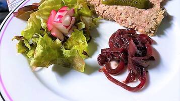 Una mesa con platos de comida, incluyendo una ensalada con rábanos y un guiso de carne con un pepinillo.