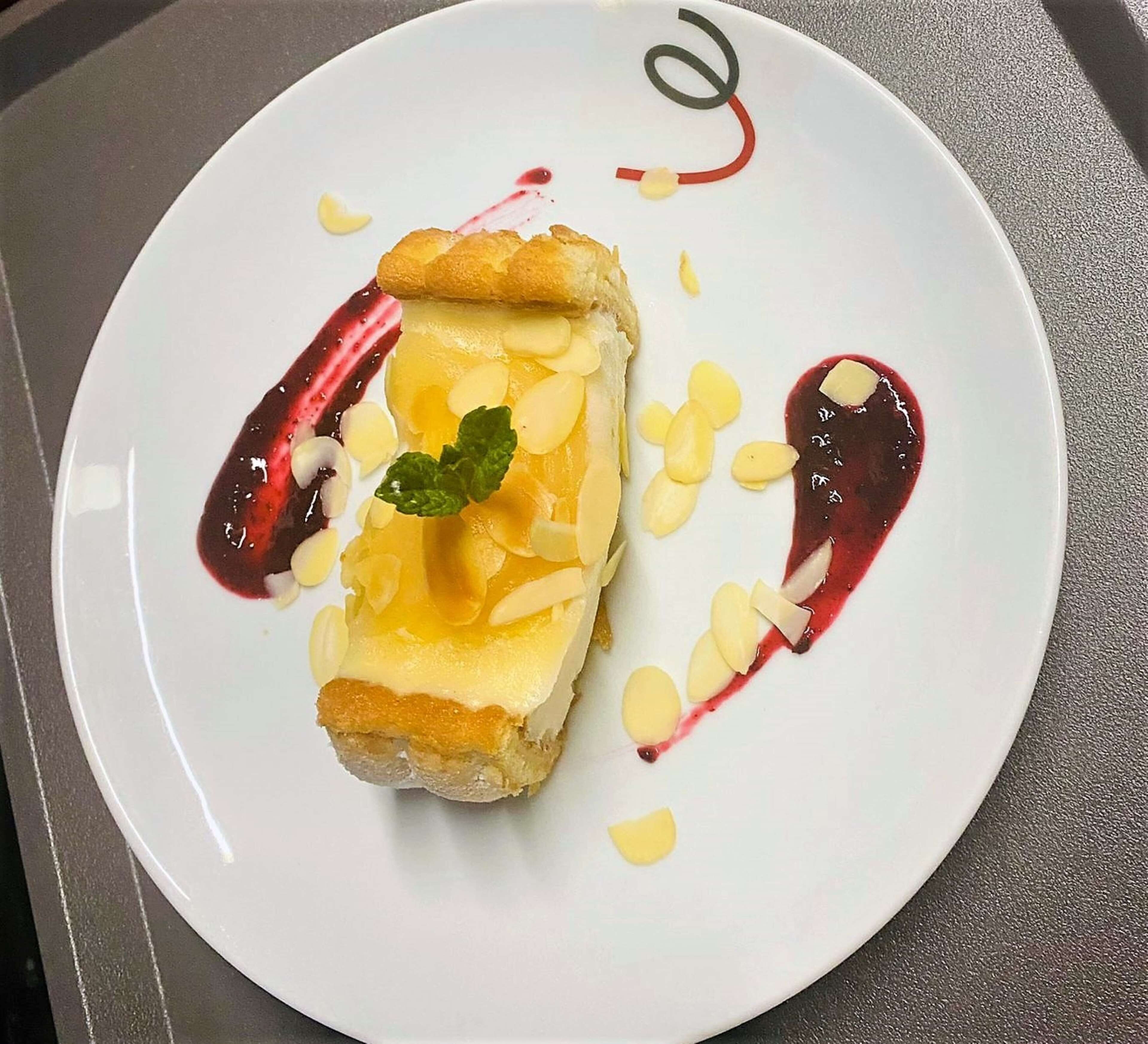 Een dessert op een wit bord met een decoratieve spiraal en een muntblaadje.
