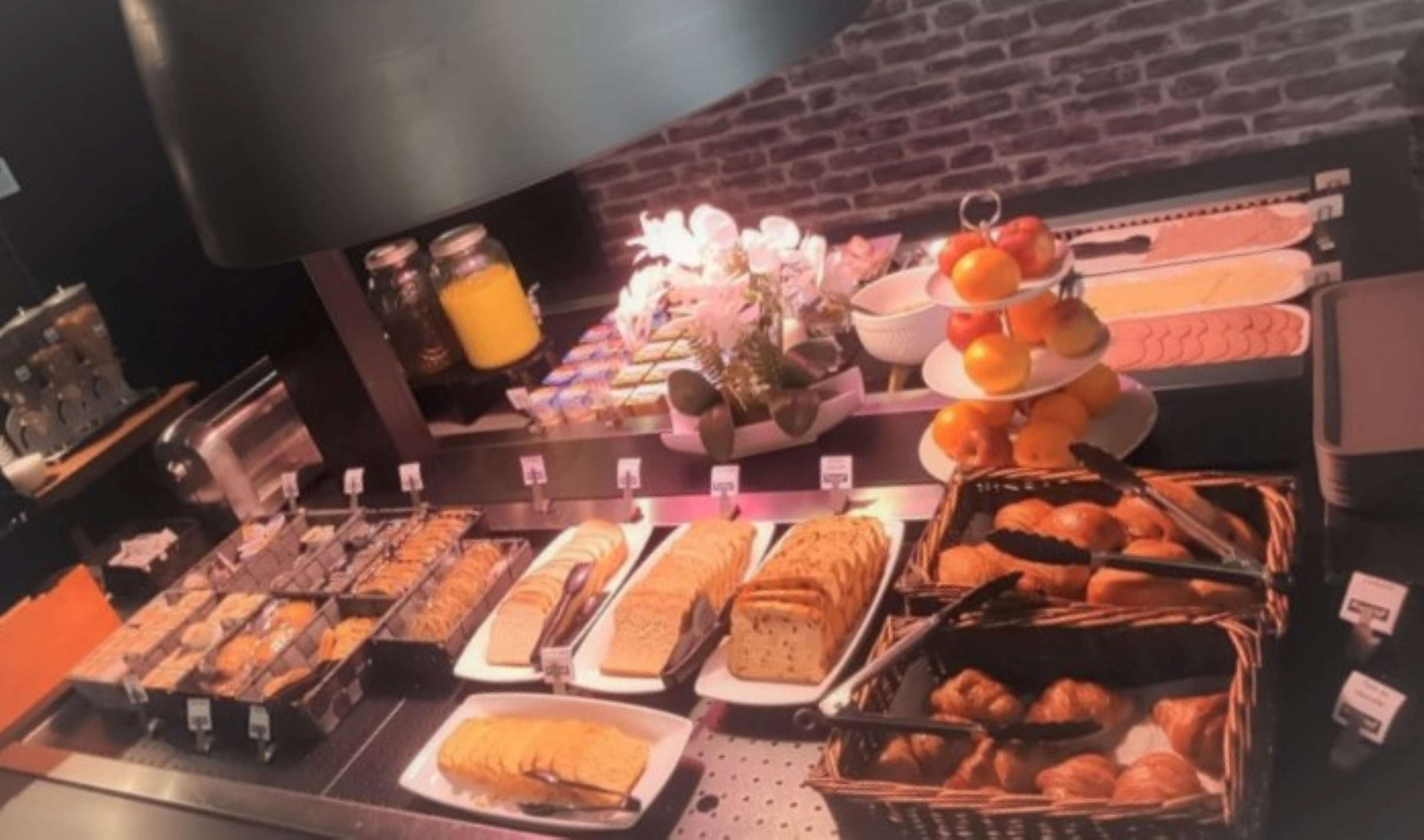 Un buffet de petit-déjeuner proposant une variété d’aliments, notamment des viennoiseries, des fruits et des jus de fruits.
