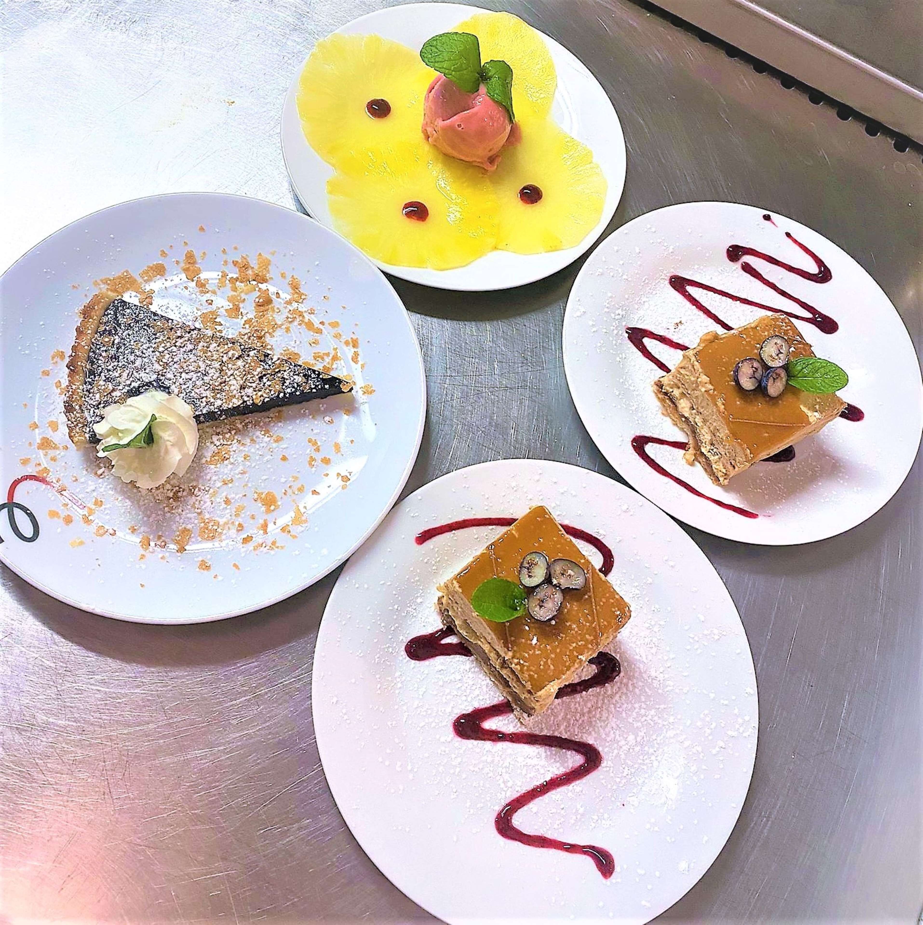 Quatre assiettes de desserts, chacune agrémentée de garnitures et de sauces différentes.