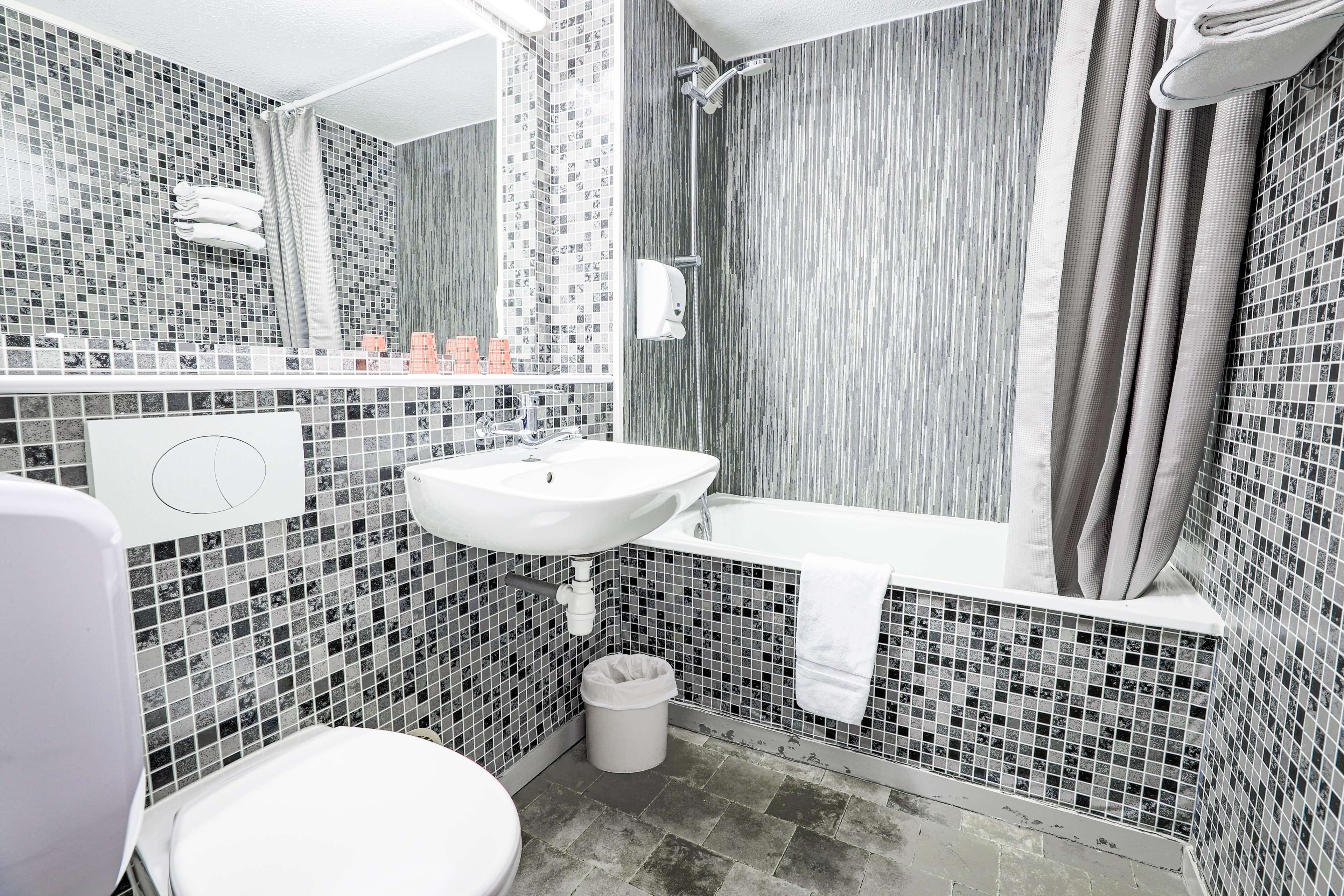Un baño con lavamanos blanco, bañera, inodoro y zona de ducha.