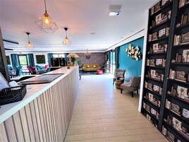 Un moderno hall de hotel con mostrador de recepción, zona de estar y una pared decorativa.