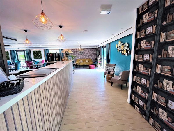 A modern hotel lobby with a reception desk, seating area, and a wall of decorative items.