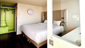 A compact hotel room with a single bed, a small bedside table, a mirror, and a green air conditioning unit. - Hotel Campanile Montargis - Amilly (Amilly)