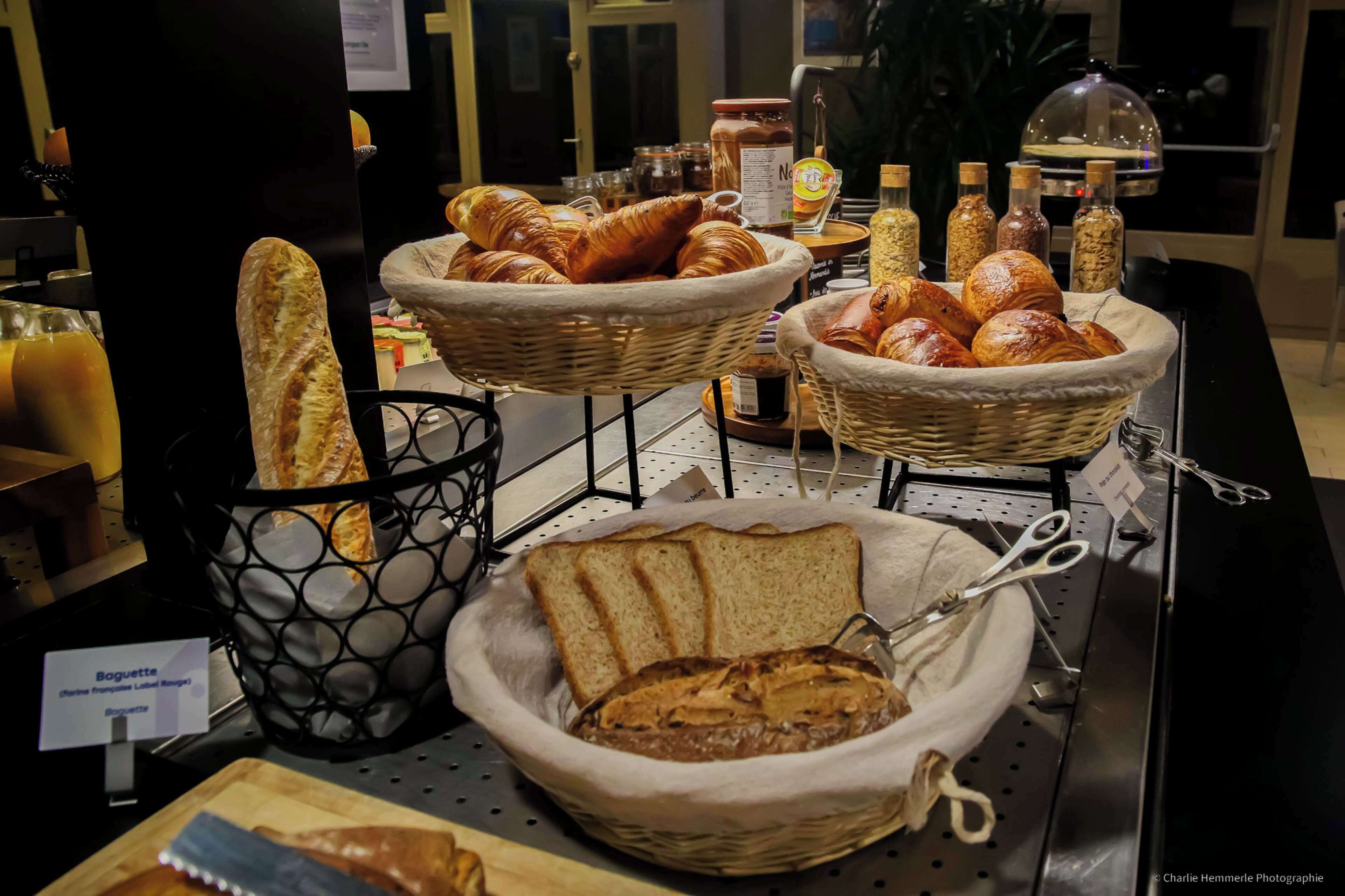 Una exhibición de panes y pasteles variados en cestas, con un letrero que indica 'Baguette (Baguette francesa)'.