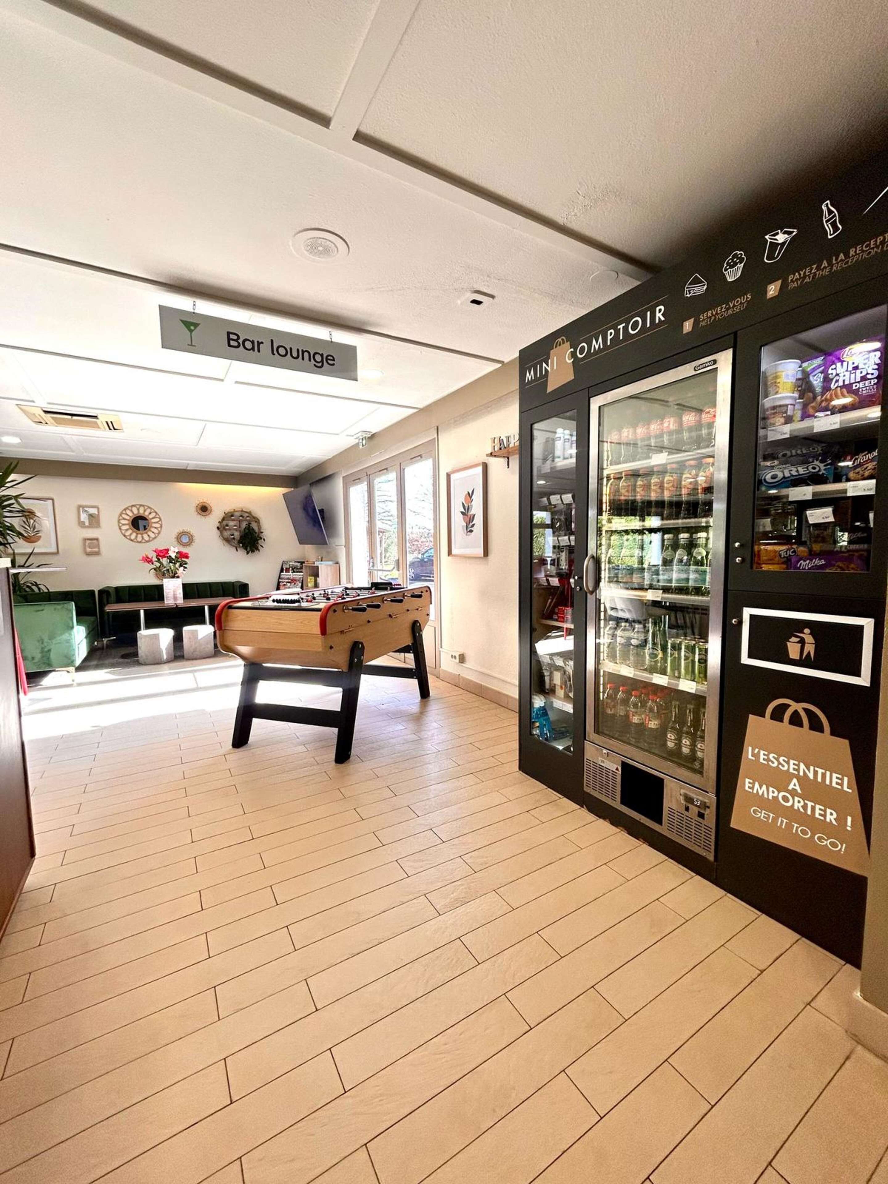 Een bar met een loungegedeelte, een tafelvoetbaltafel, een minibar en een automaat.