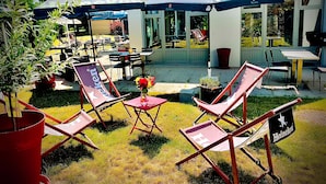 An outdoor seating area with foldable chairs and tables, covered by umbrellas, and a sign with the Heineken logo. - Hotel Campanile Montargis - Amilly (Amilly)