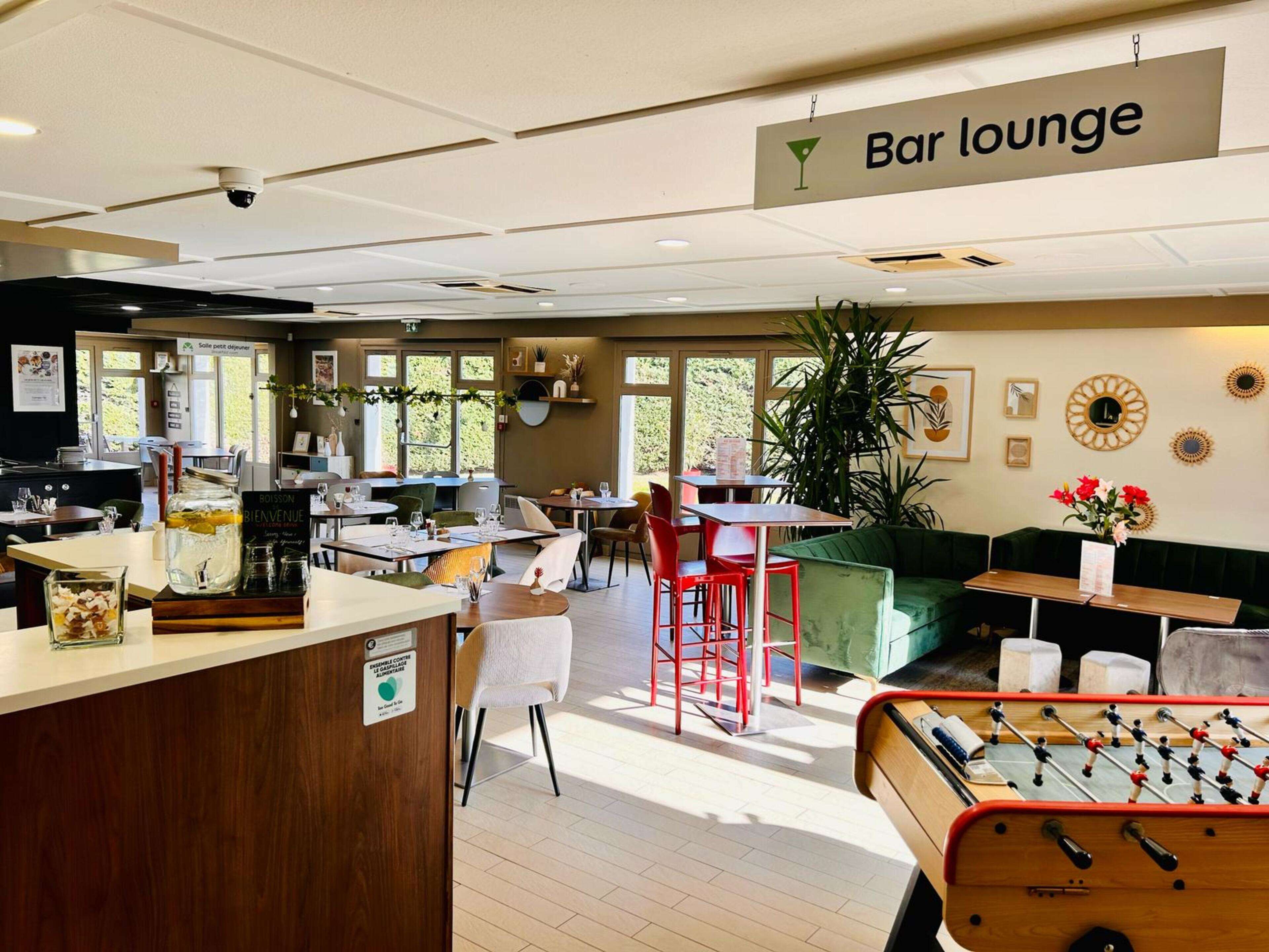 A bar lounge with a foosball table, a green sofa, and a sign indicating the lounge area.